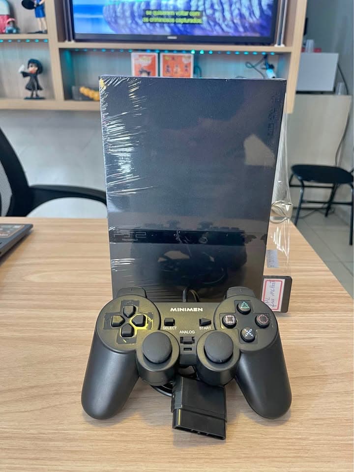 PlayStation 2 slim protegido por plástico, com controle com fio à frente